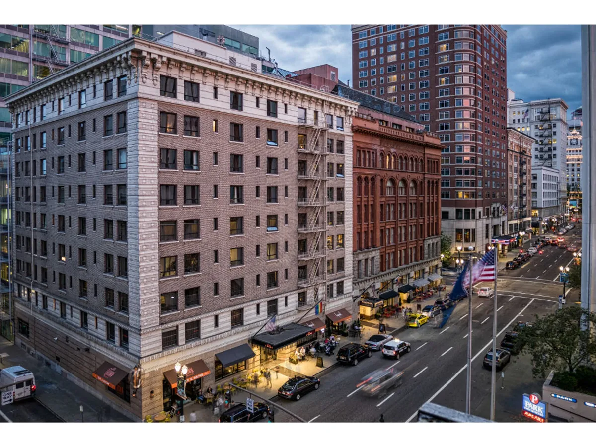 The photo showcases lively street activity with historic buildings, outdoor dining areas, and people walking along the sidewalks. The bustling ambiance reflects a city alive with events, dining, and exploration.