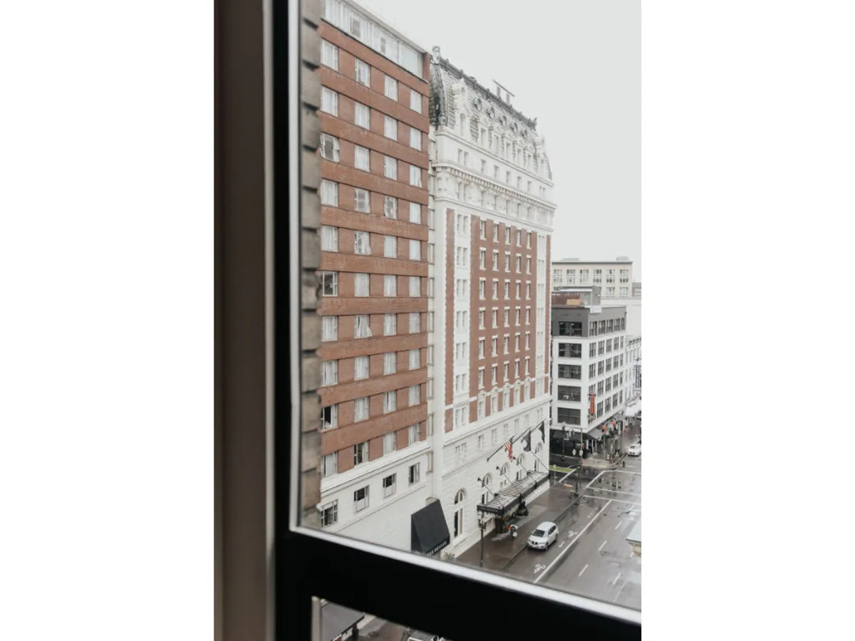 A reflective view of historic building architecture along an urban street, with rain-slicked pavement capturing Portland’s cozy, contemplative mood. The scene invites leisurely exploration of nearby neighborhoods.