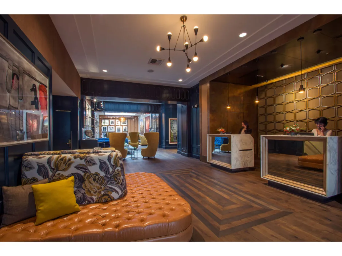 A chic, inviting lounge area with modern seating, reception desks, and curated artwork on the walls. The space encourages guests to socialize, relax, or catch up on work, reflecting the welcoming communal spaces of the hotel.
