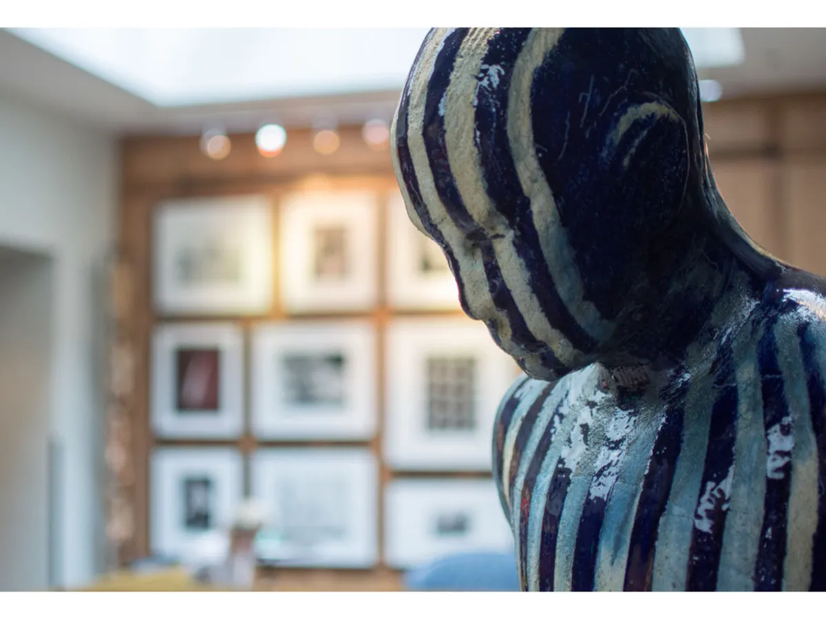 A sophisticated gallery wall with framed art and a sculptural piece catches the eye, set against a backdrop perfect for art appreciation and thoughtful conversation. The space appears intimate and creative, echoing the boutique, gallery-inspired arrival experience described in the section.