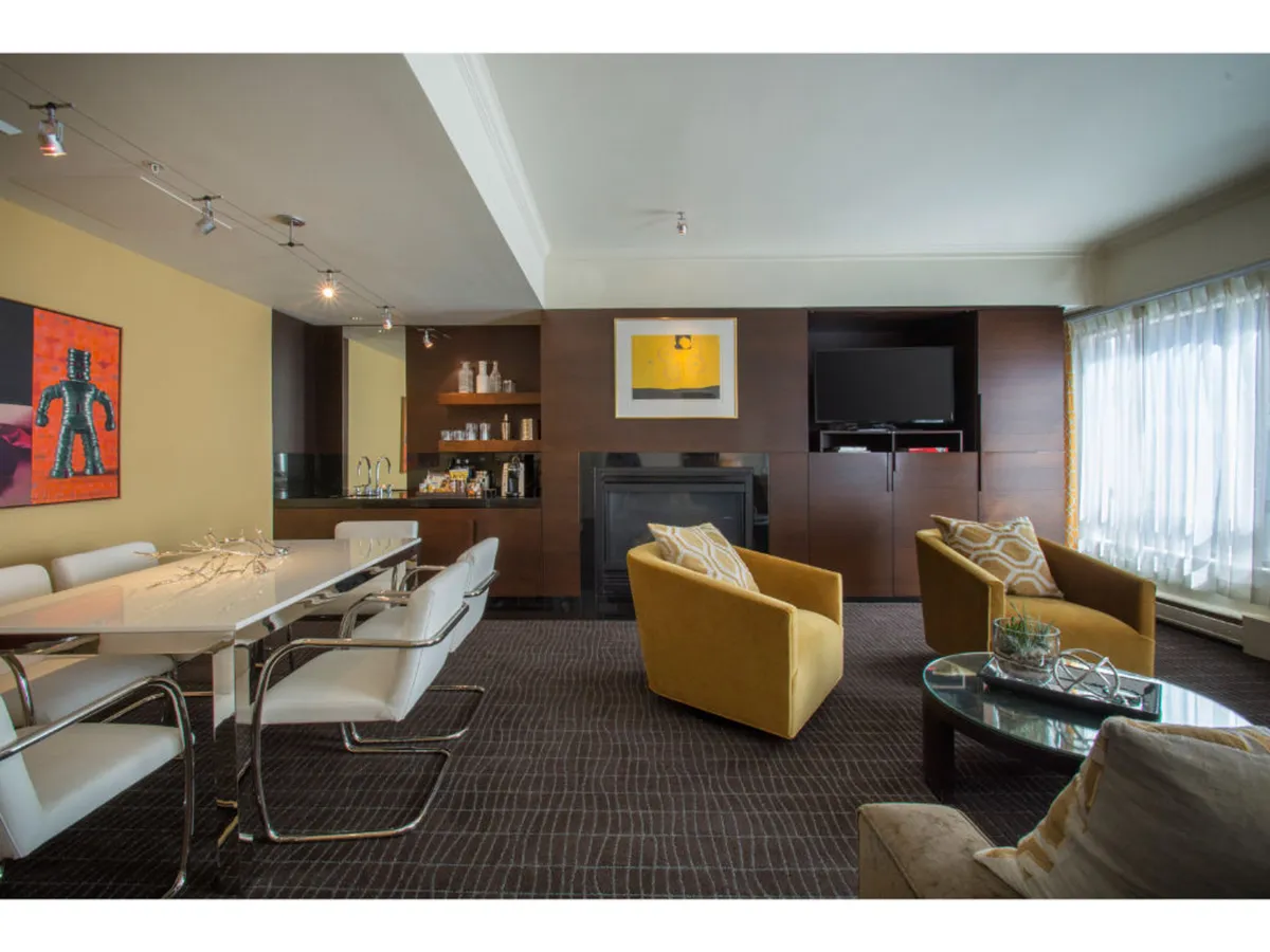 A cozy dining space with a central table, bright yellow armchairs, and contemporary artwork, ideal for shared meals or quiet moments by the fire. The mood is both lively and comfortable, inviting families and groups to gather.
